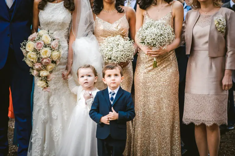 Bride, bridesmaids in gold sequins, flower girl and page boy holding gypsophila bouquets