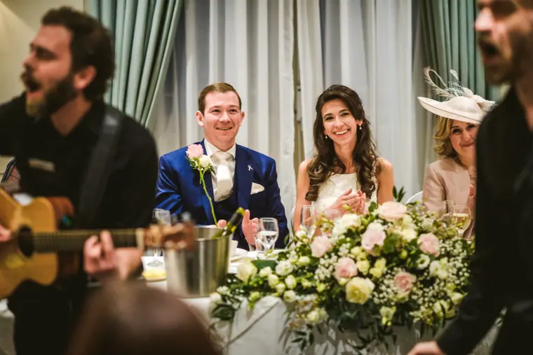 Singing waiter with a guitar serenading the laughing couple at the top table