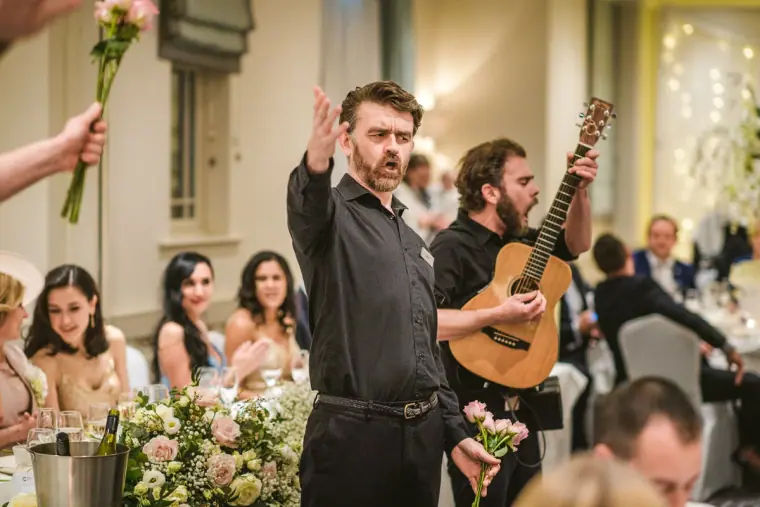 Singing waiters with roses and a guitar performing among the tables
