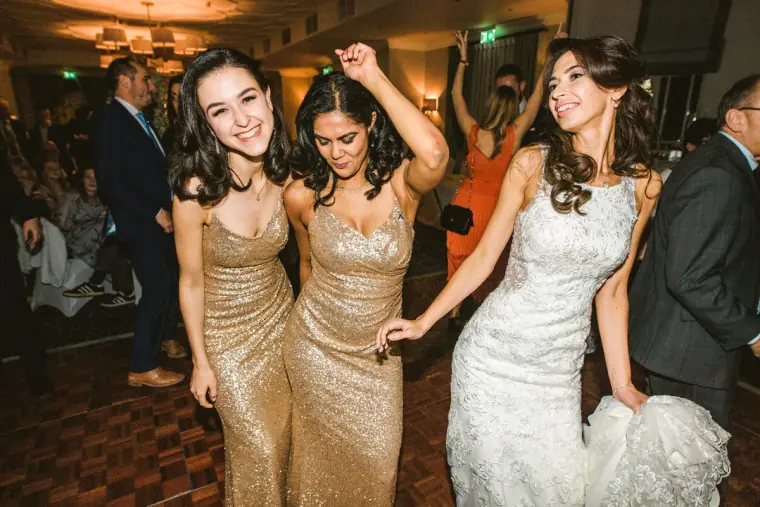 Elina dancing with two bridesmaids in gold sequinned dresses