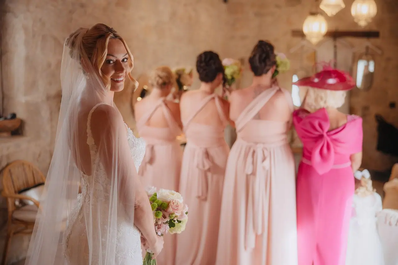 Zoe glancing back with a smile as her bridesmaids in blush pink wait to turn round