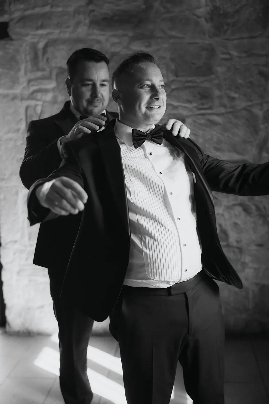 Black-and-white photo of Oliver laughing as his jacket goes on