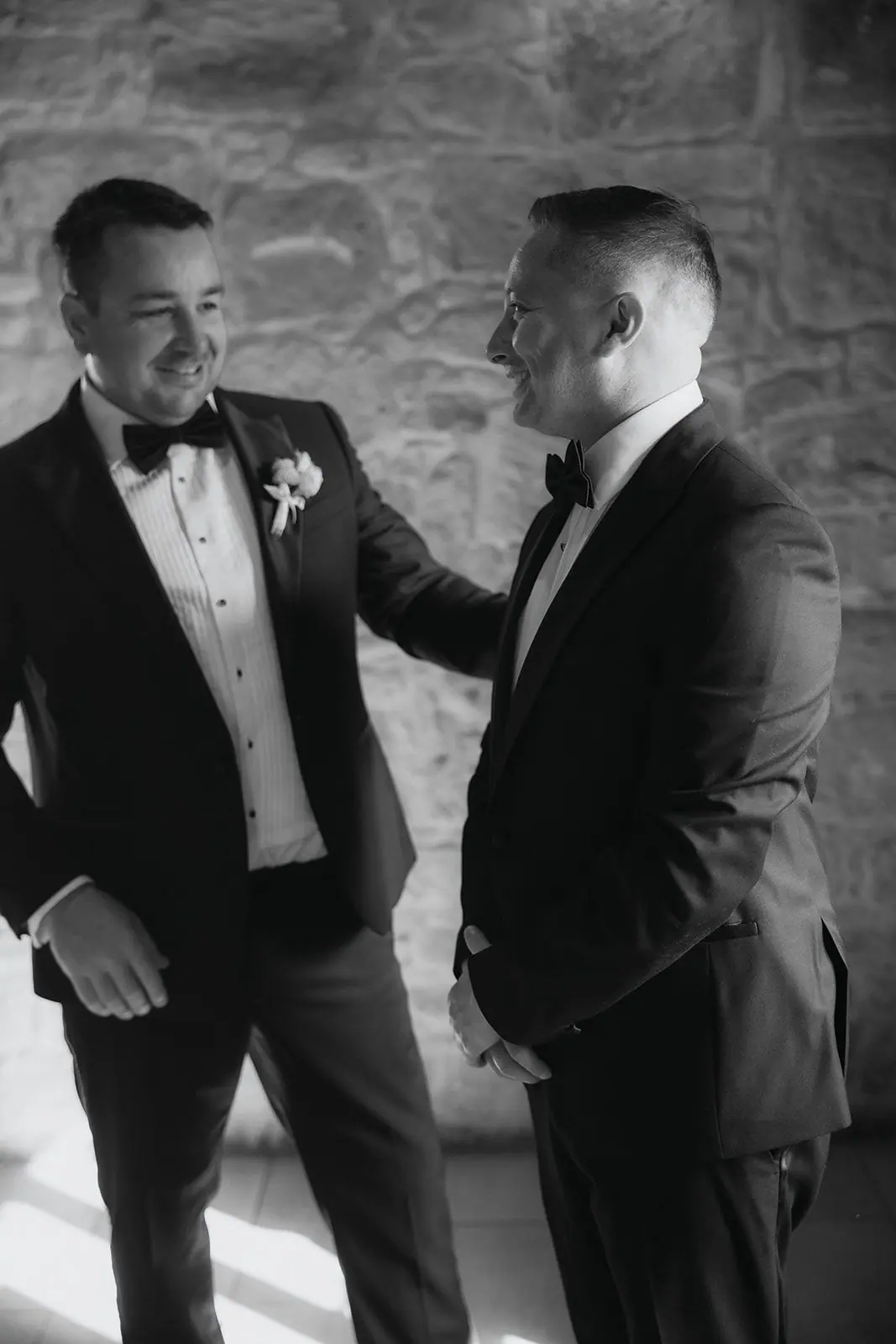 Black-and-white photo of Oliver and a groomsman sharing a joke