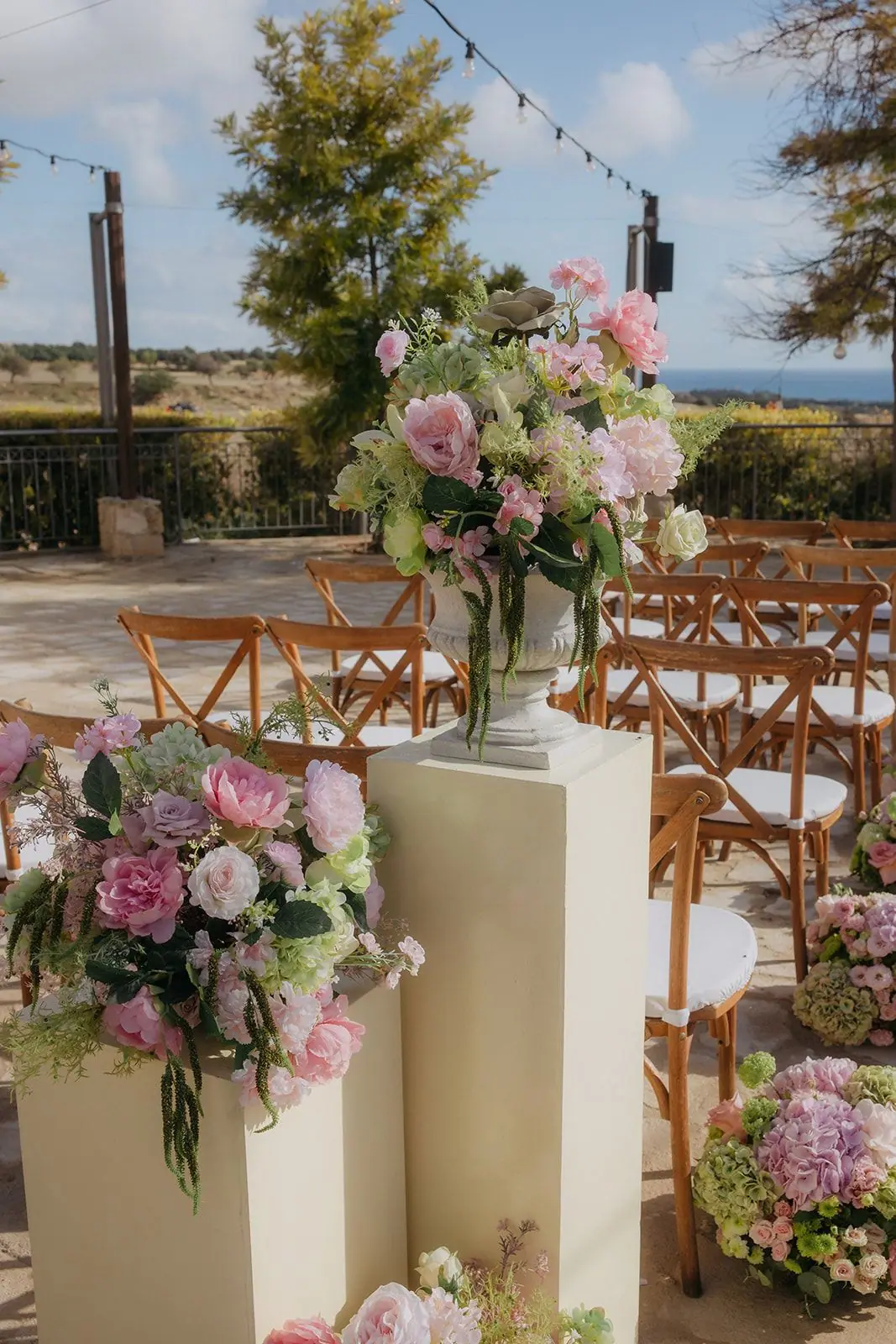 Pink and green floral arrangement on a cream plinth beside the aisle