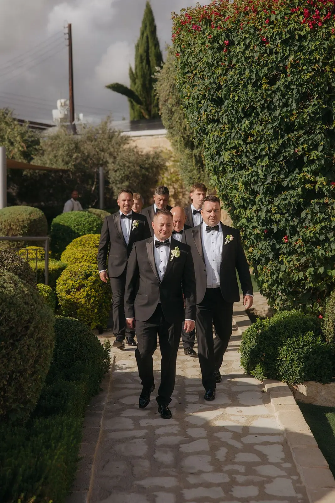Oliver and his groomsmen walking through Liopetro's topiary gardens to the ceremony