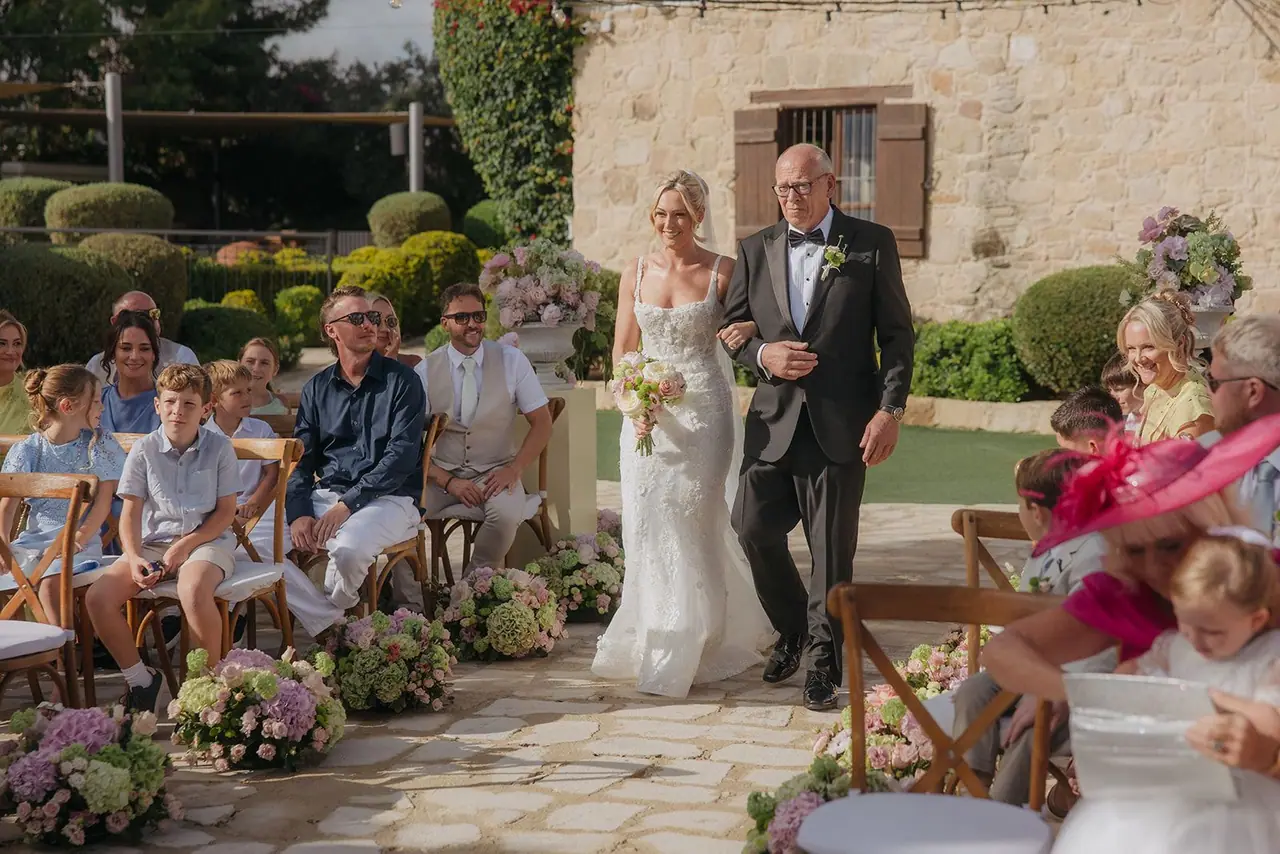 Zoe and her dad walking down the aisle past smiling guests