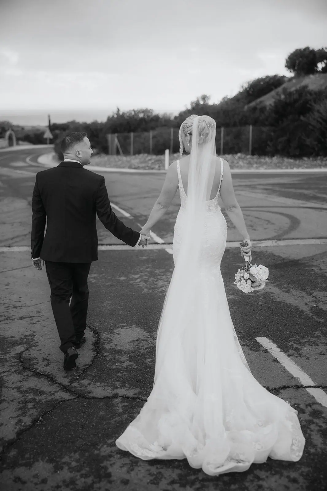 Black-and-white photo of Zoe and Oliver walking hand in hand down the empty road