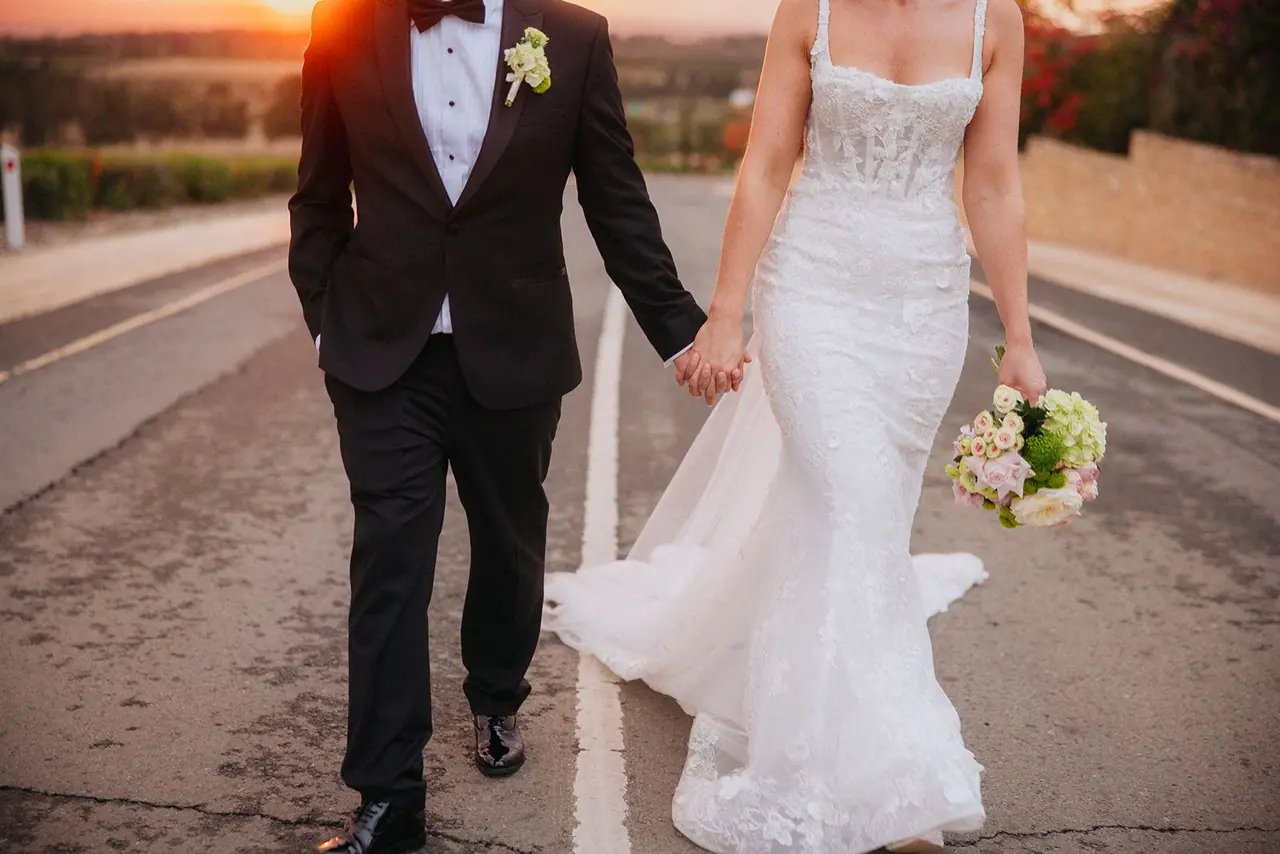 Close-up of Zoe and Oliver walking hand in hand, her bouquet at her side