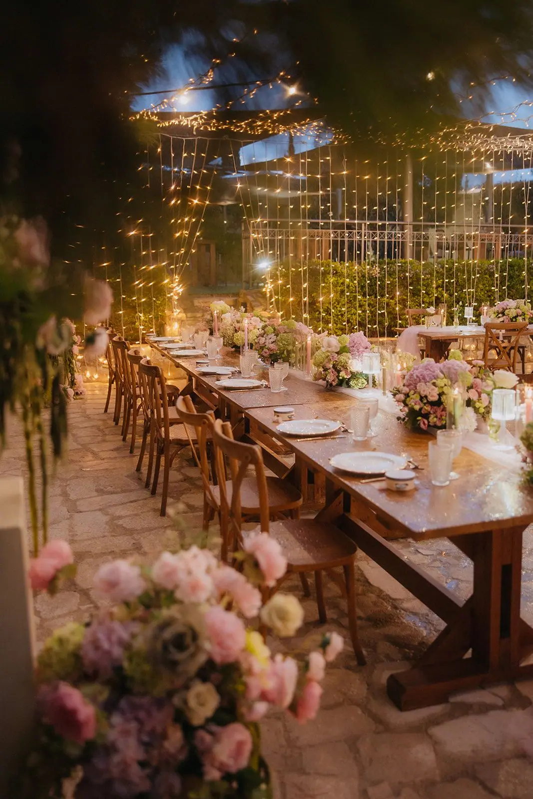 Long table framed by flowers beneath the fairy-light canopy