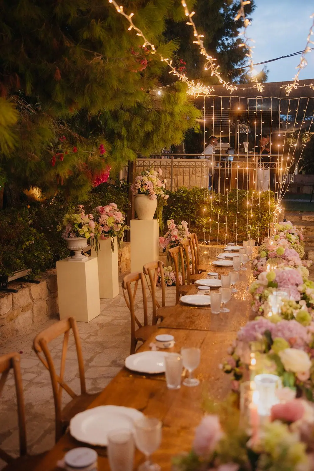 Reception table lined with flowers and candles under fairy lights