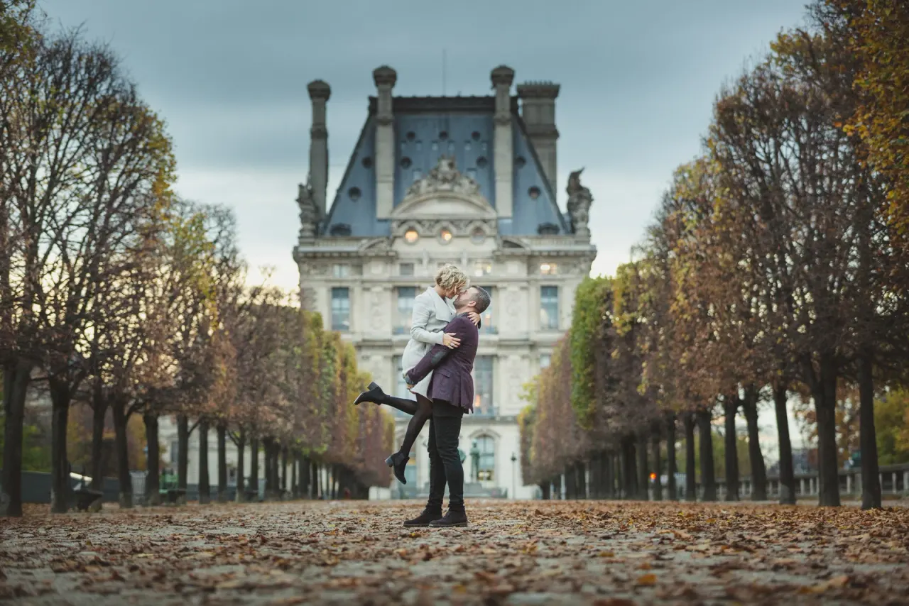 Nick lifting Aimie off her feet in a leaf-strewn tree-lined avenue in Paris