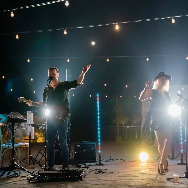 Duo performing on an outdoor stage under festoon lights and spotlights