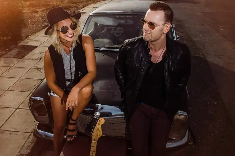 Aimie Wild and a guitarist sitting on the bonnet of a vintage car