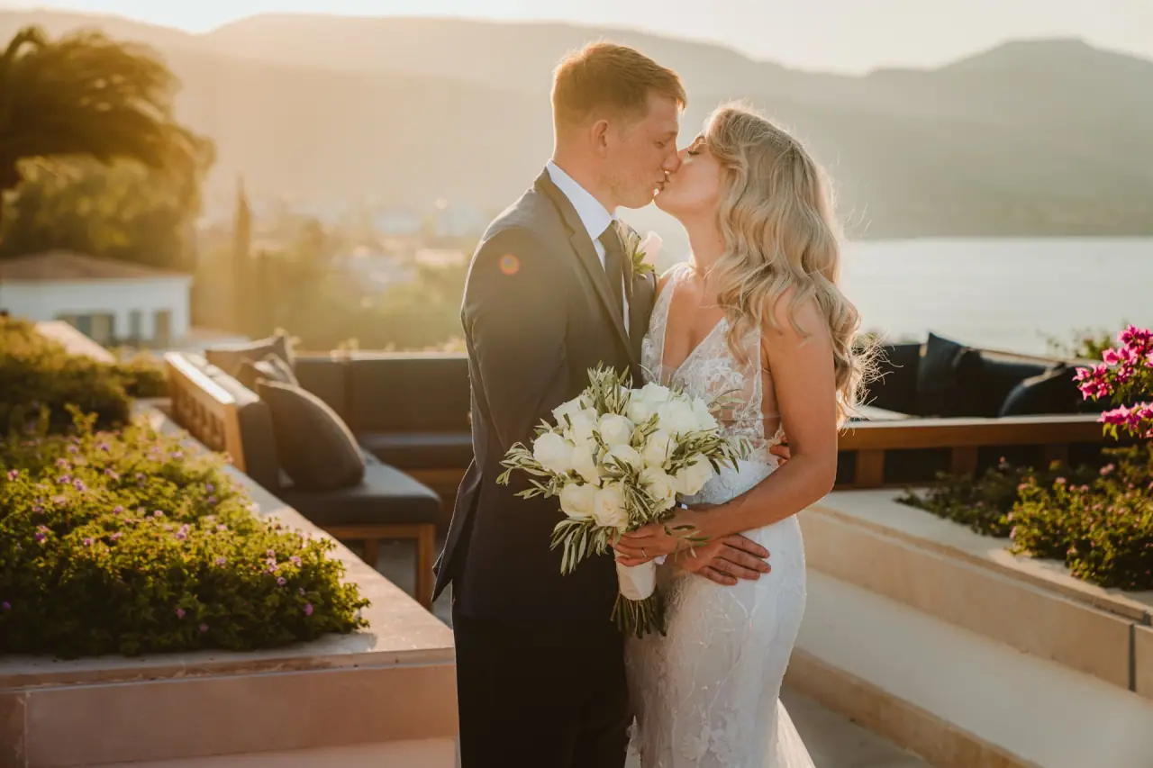 Carly and Jack kissing at golden hour on a sea-view terrace at Anassa Hotel, Latchi