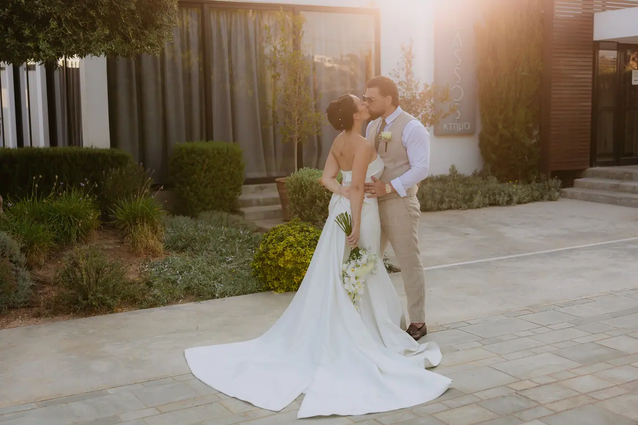 Bride and groom kissing in golden evening light outside Alassos, Kissonerga, Paphos