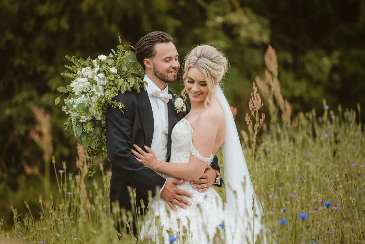 Abby and Taz embracing in a wildflower meadow at Ardington House, Oxford
