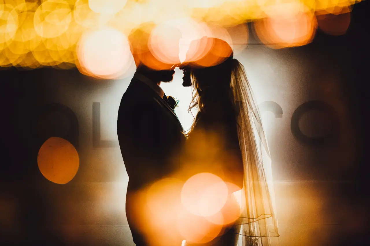 Silhouetted bride and groom touching foreheads amid warm golden bokeh