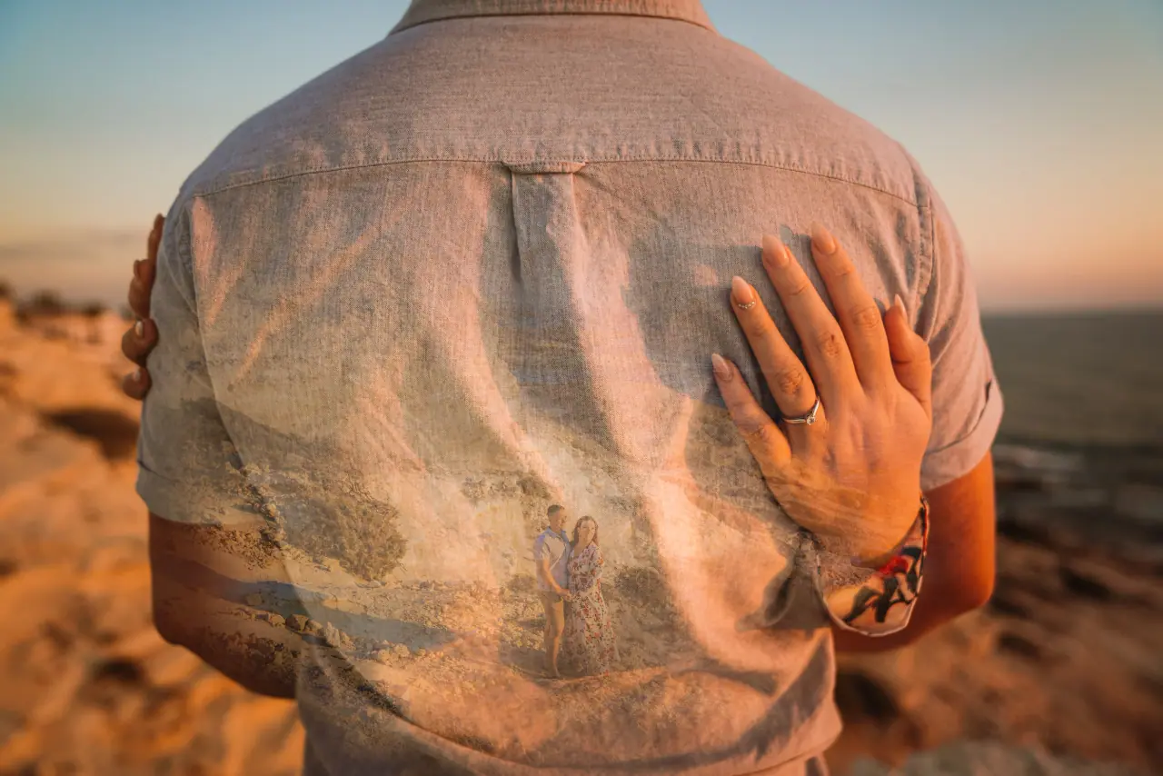 Alice's hand resting on Tom's shirt at sunset during a mini shoot at the Sea Caves, Paphos