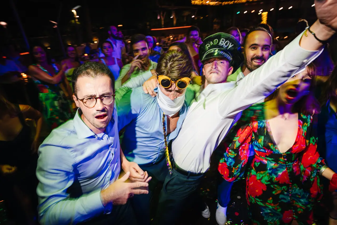 Guests in novelty caps and glasses partying wildly on the dancefloor