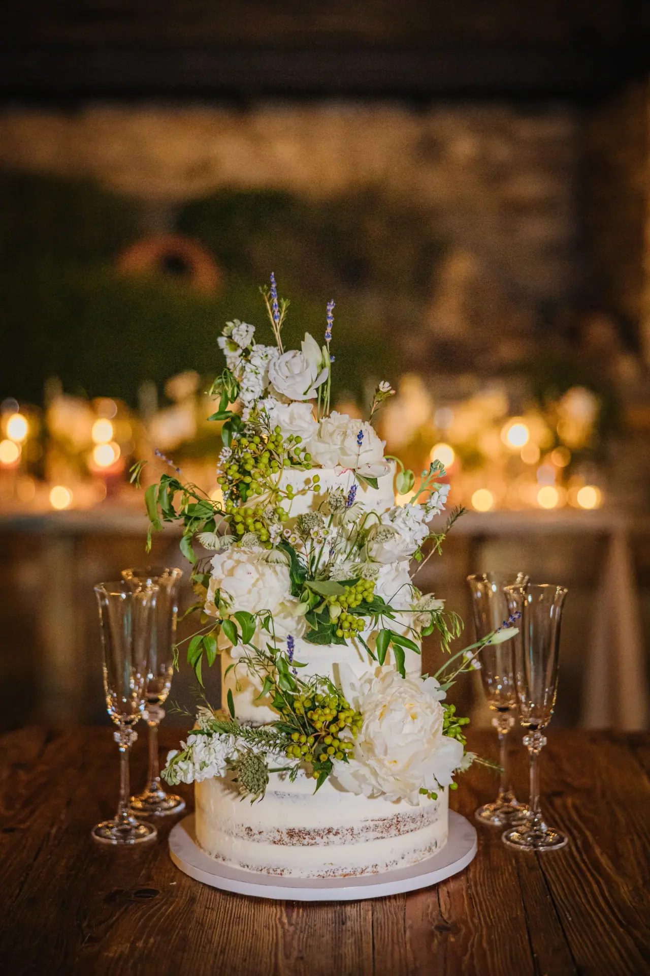Wedding cake dressed with white flowers and greenery among candles at Dafermou