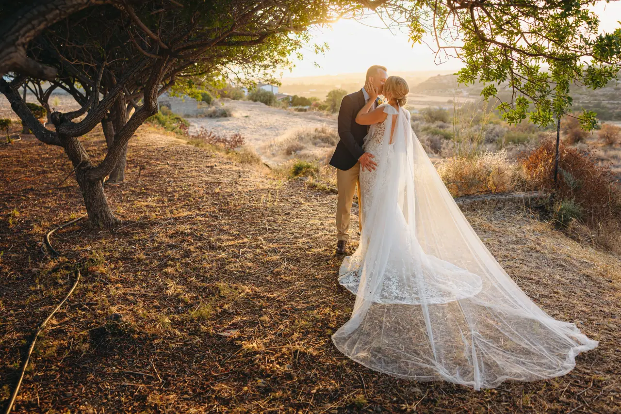 Beth and Josh kissing beneath a gnarled tree at golden hour, her veil trailing, Liopetro, Kouklia