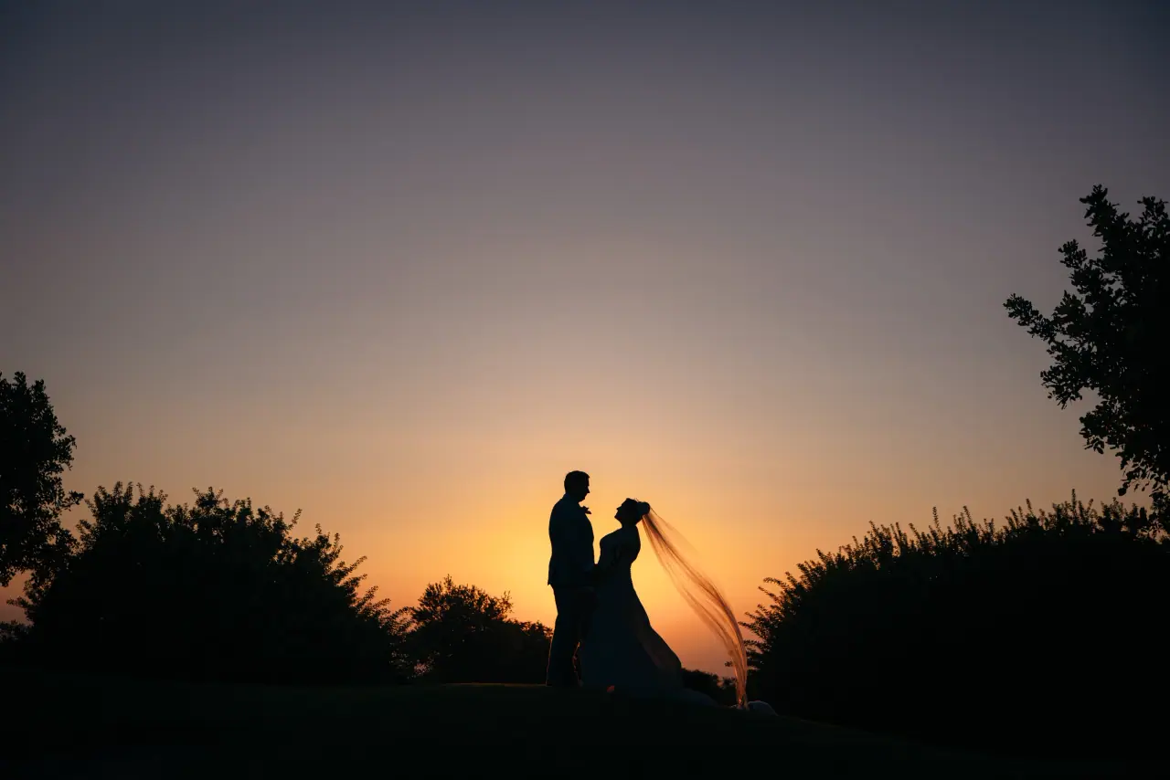 Diana and Peter silhouetted at sunset, her veil lifting, Aphrodite Hills