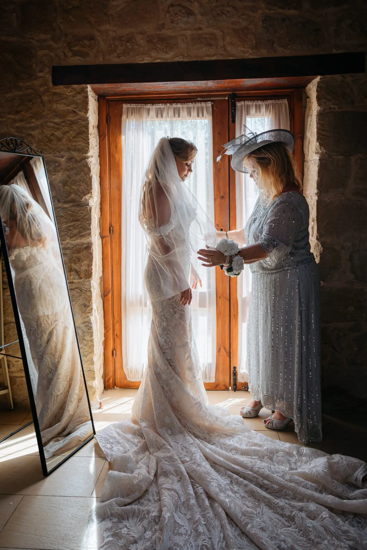 Annie with a guest in a hat by a window, her long train spread on the floor, Liopetro