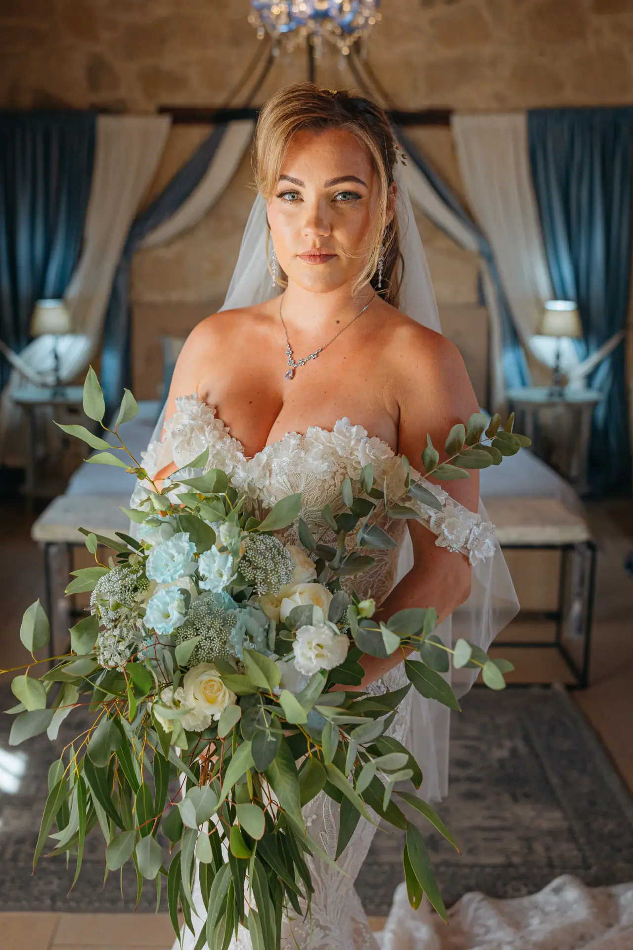 Annie holding her eucalyptus and white rose bouquet in the bridal suite