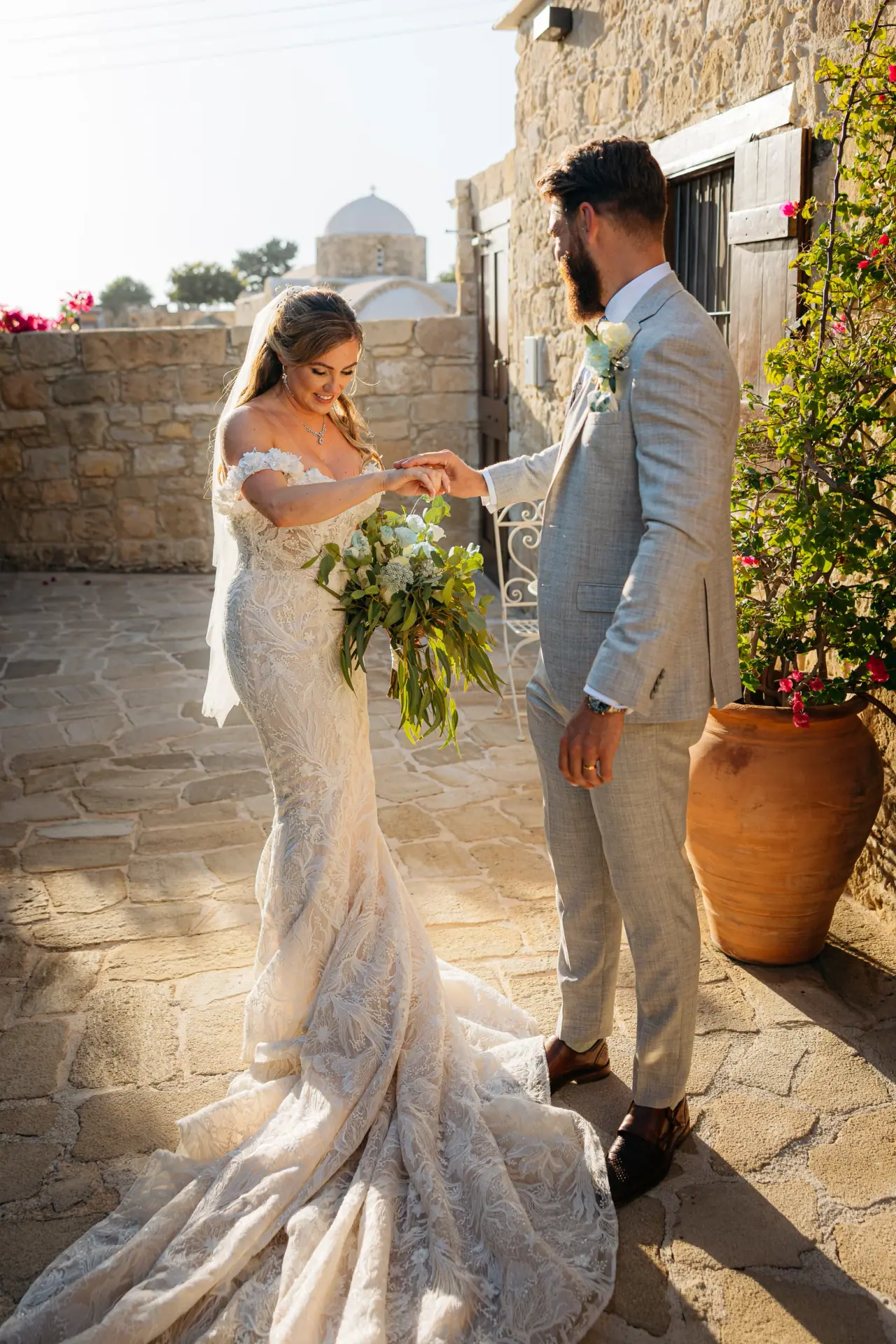 Iain leaning in to Annie in a sunlit stone courtyard at Liopetro