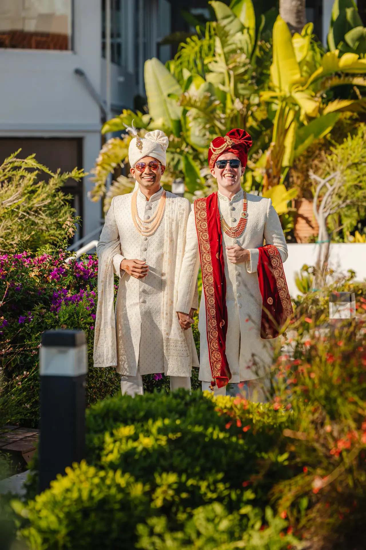 Daniel and Prashant in sherwanis and turbans in a tropical garden