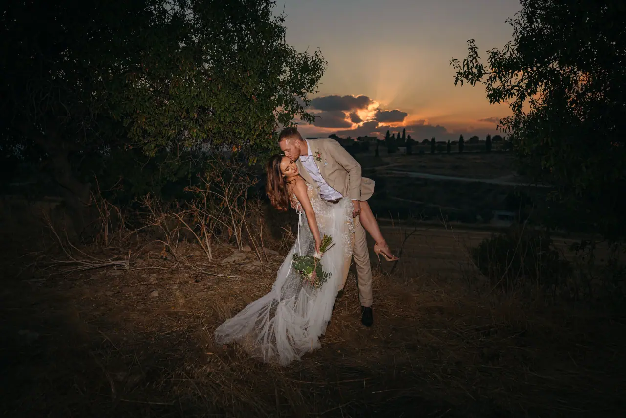 Groom dipping his bride in a field at dusk at Liopetro