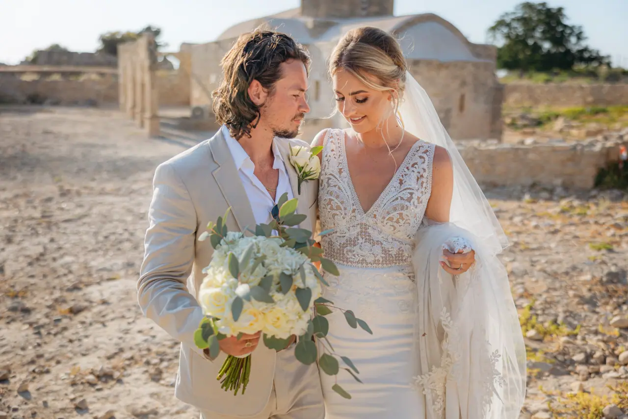 Megan and Greg sharing a look with her bouquet before a stone chapel at Liopetro
