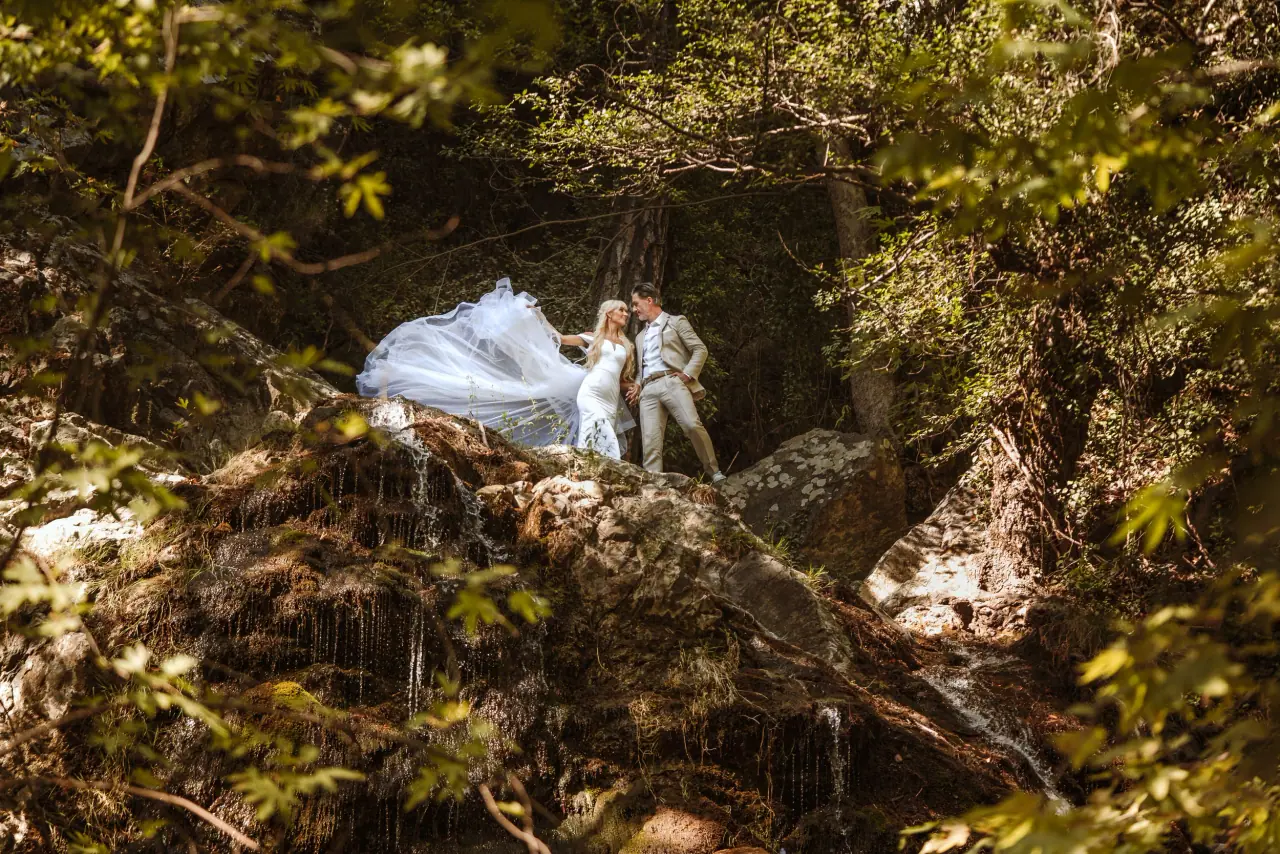 Disa and John on mossy rocks beside a waterfall in the Troodos forest