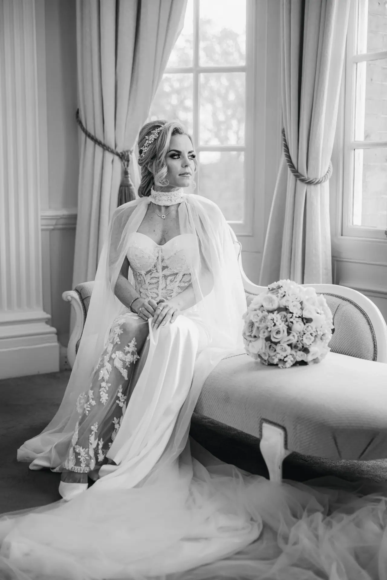 Black-and-white photo of Jade on a chaise in her gown and cape beside tall windows, Hedsor House