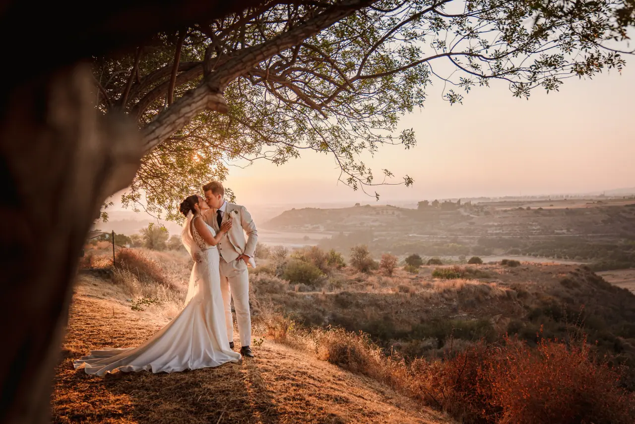 Jessica and Curtis embracing under a tree overlooking a valley at golden hour, Liopetro