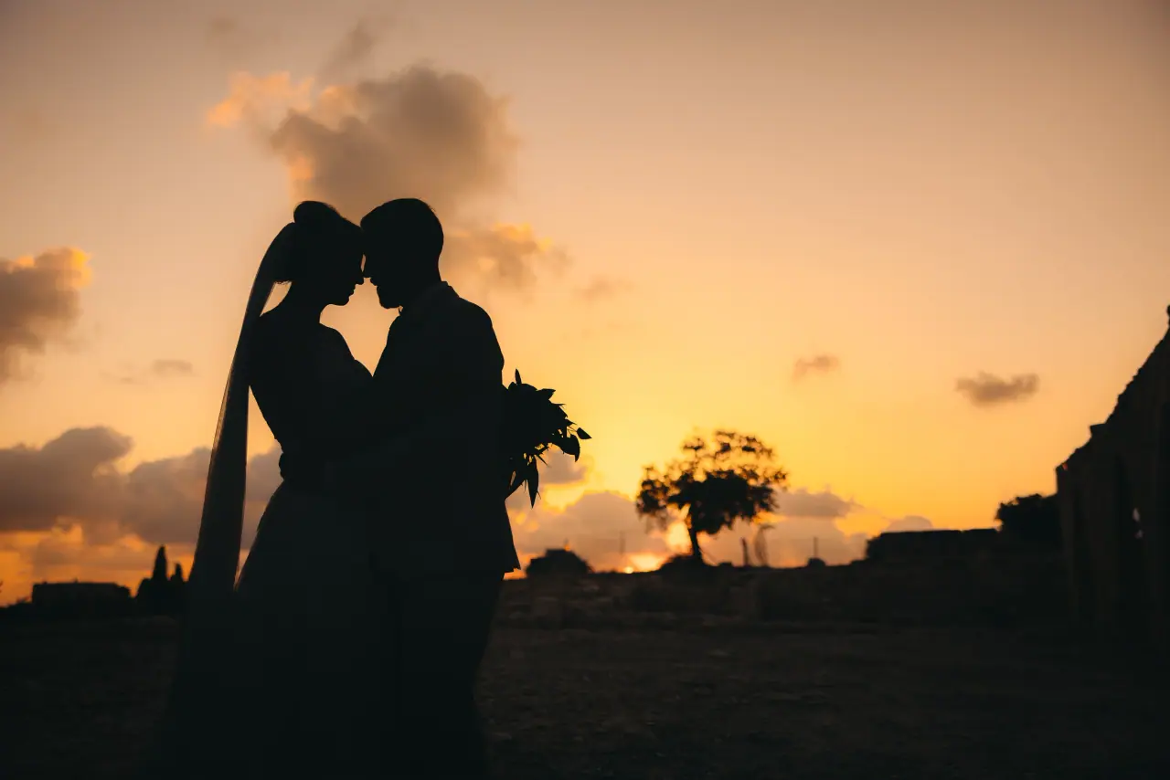 Katie and James silhouetted touching foreheads at sunset
