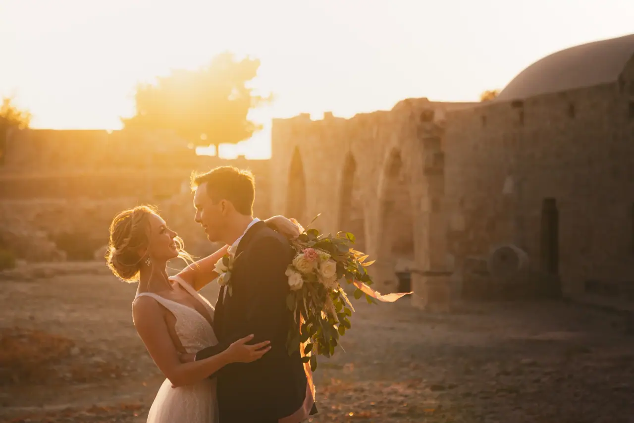 Kristina holding Jamie close among stone ruins in the setting sun, Liopetro, Kouklia