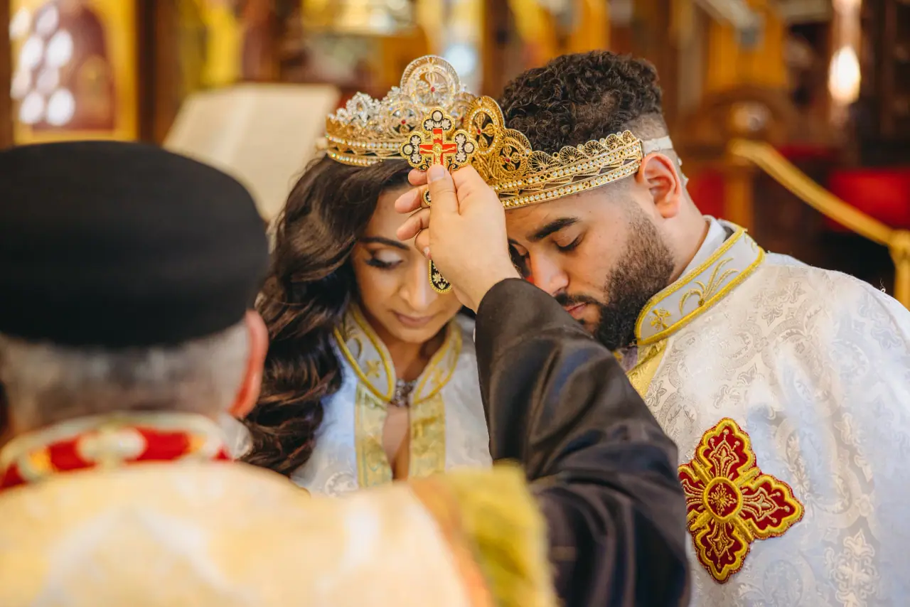 Bride and groom wearing ornate crowns during an Orthodox crowning ceremony