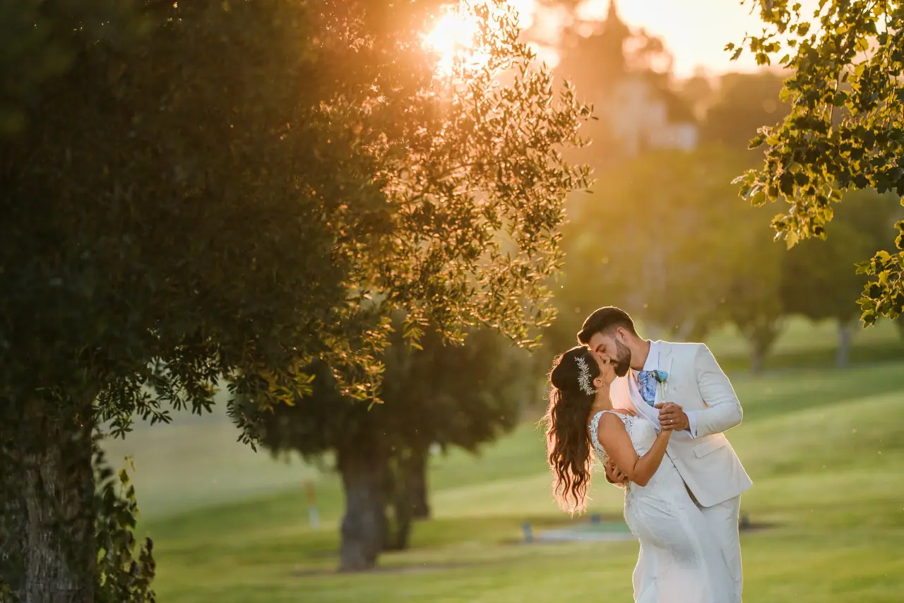 Danielle and Phillip kissing in golden-hour light at Minthis Hills, Paphos