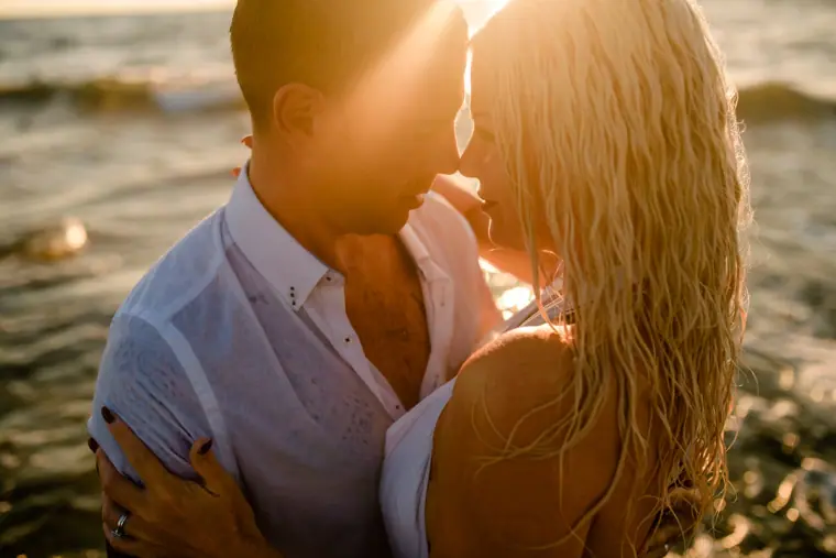 Maryellen and Ben face to face in the sea at sunset, hair wet